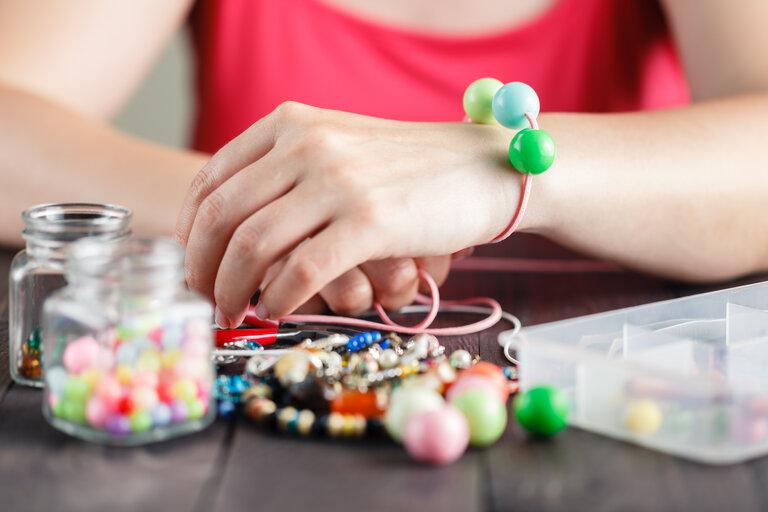 Woman's hands making bracelete with plastic beads